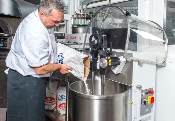 boulanger versant la farine dans le pétrin